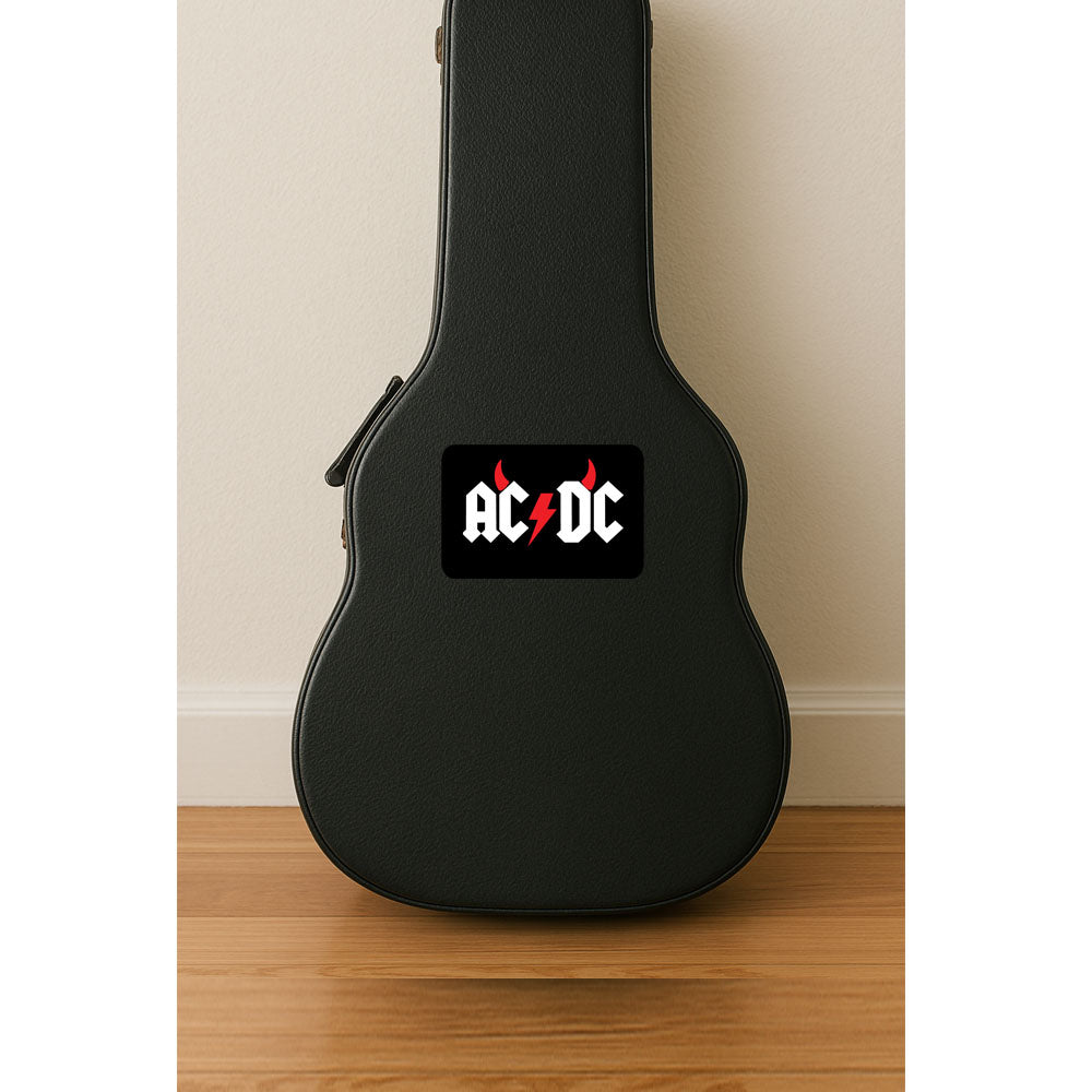 Black guitar case with AC/DC logo on a wooden floor against a beige wall.
